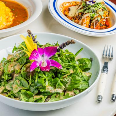 A table with Mushroom Confit Salad, grilled corn ribs, and an omelet dish.