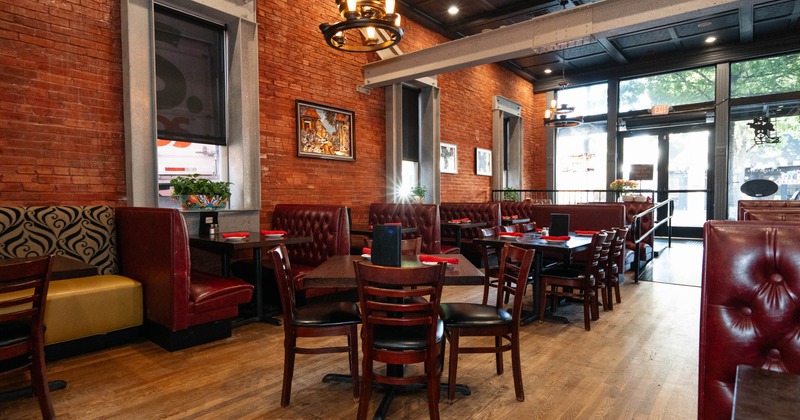 Interior, brick walls, red leather booths, dark wood tables, and chandeliers
