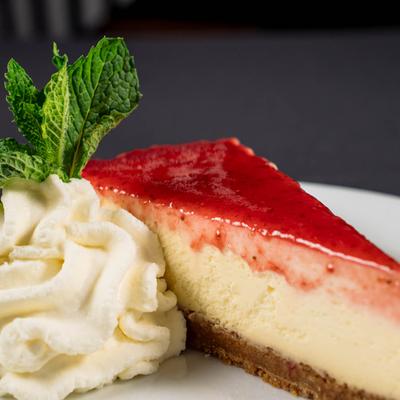 Strawberry cheese cake  with whipped cram and mint leaves.
