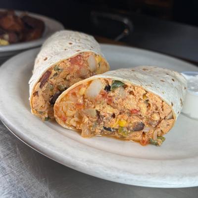 Breakfast burrito, sliced in half and served on a plate.