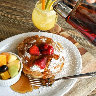 Buttermilk Pancakes served with fresh fruit and a cocktail drink.
