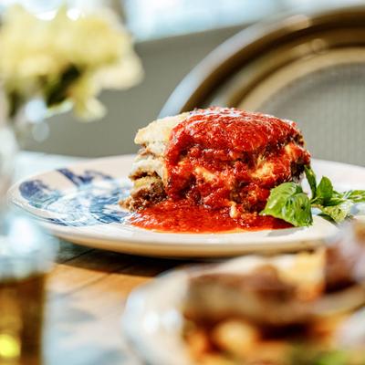 Lasagna topped with a tomato sauce and garnished with fresh basil.