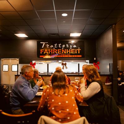 View at the table with the gusts seated and restaurant's sign in the background.