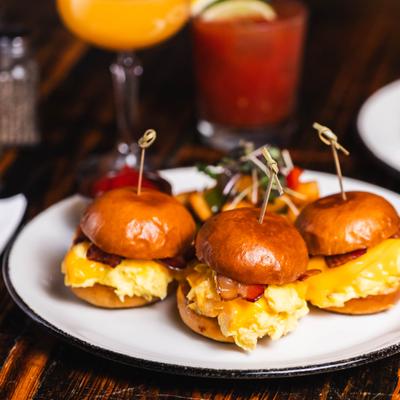 Breakfast sliders with cocktails in the background.