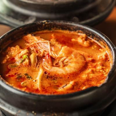 Seafood Sundubu served in earthenware pot, close-up.