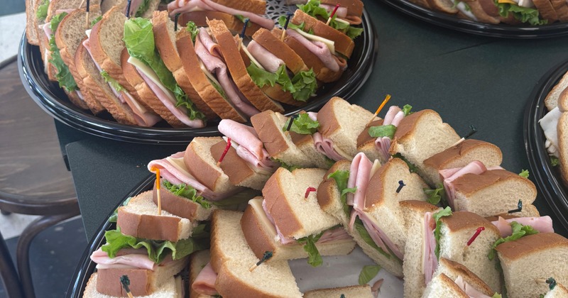Platters of stacked deli sandwiches with turkey, lettuce, and colorful toothpicks