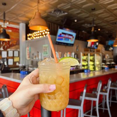 A hand holding a cocktail against a bar backdrop.