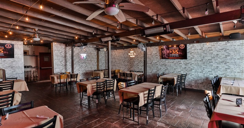 Interior, seating area, tables for four, ceiling fans, exposed ceiling beams, brick walls