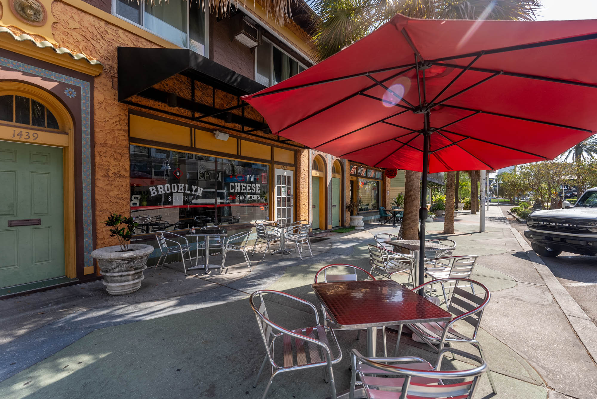 Tables and chairs under parasols outside of the restaurant