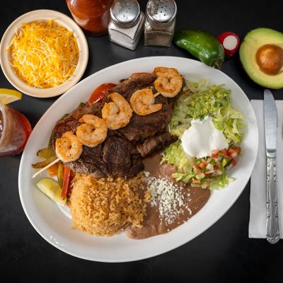 Rib eye steak with shrimp skewer, beans, rice, lettuce, sour cream, pico, guacamole.