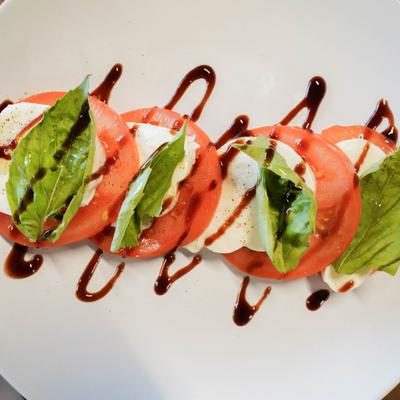 Slice of the Green with tomatoes mozzarella and greens.