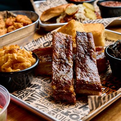 Barbecue ribs served mac and cheese, cornbread, and collard greens on a tray.