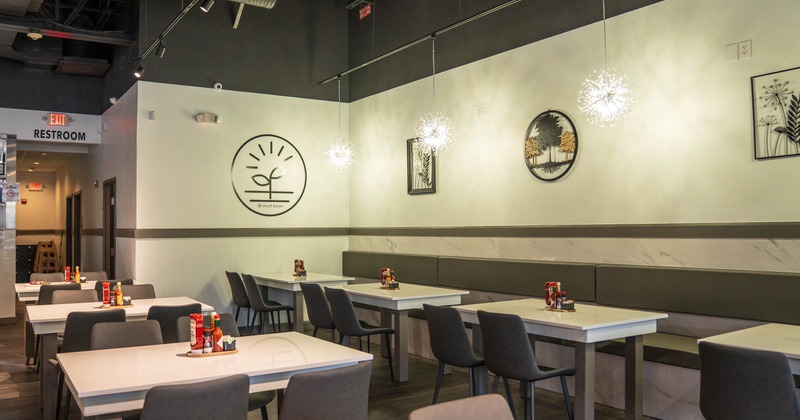 Interior of a modern restaurant with minimalist design, featuring grey chairs, white tables