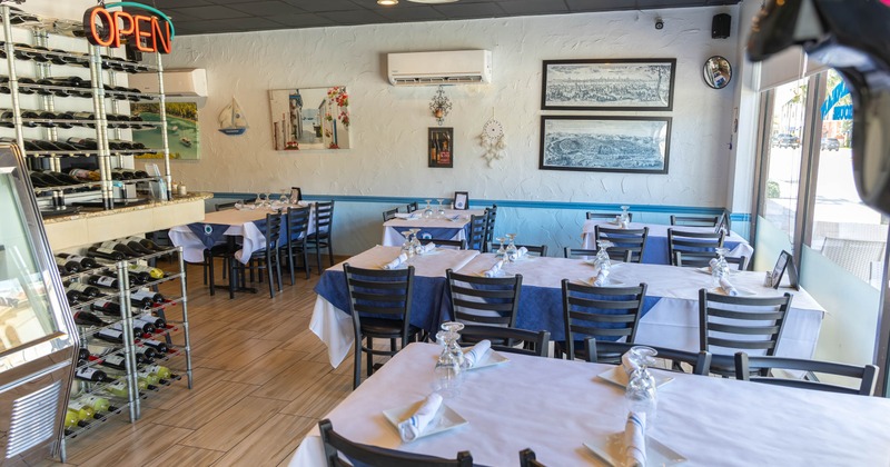 Interior of a restaurant with white and blue tables, wine rack