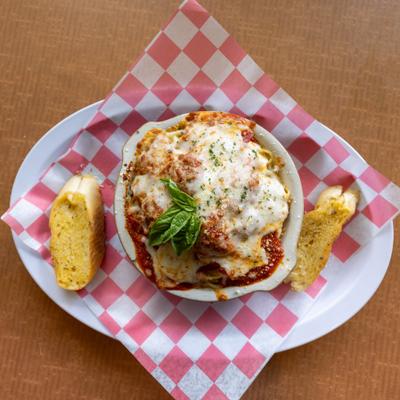 Baked spaghetti with meatballs topped with melted cheese and basil, served with garlic bread.