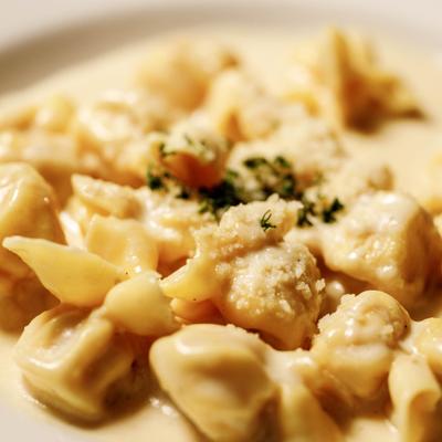 Fiocchi pasta in cream sauce, topped with grated cheese and herbs, close-up.