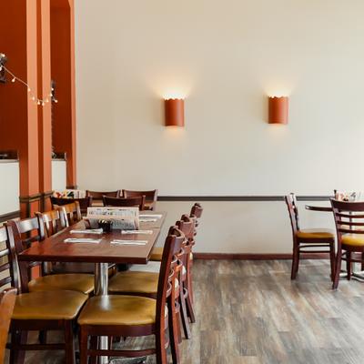 Interior featuring wooden tables and plain white walls with cylindrical light fixtures.