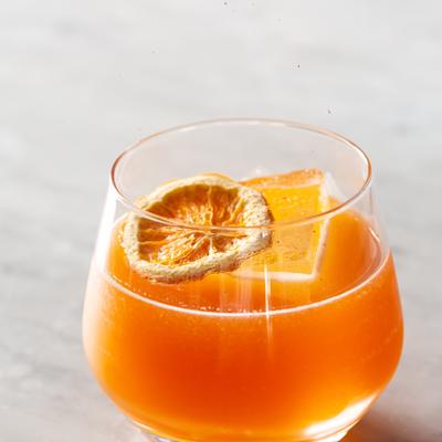 Orange cocktail garnished with dry citrus slice