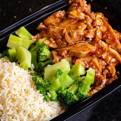 Grilled sliced meat with sauce, rice and green vegetables on the side closeup
