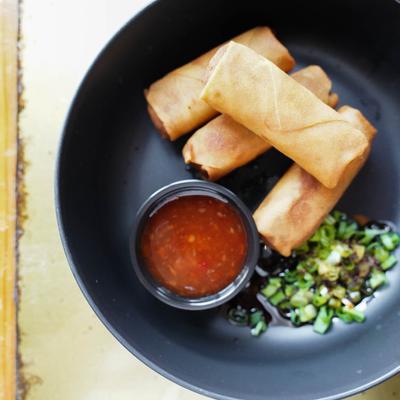 Spring rolls with dipping sauce and chopped scallions.