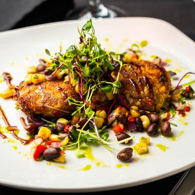 Crab cakes topped with corn and black bean salsa and microgreens.