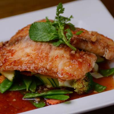 Pan-seared fish fillets served over a bed of stir-fried vegetables.