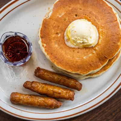 Overhead view of buttermilk pancakes with sausages and maple syrup.