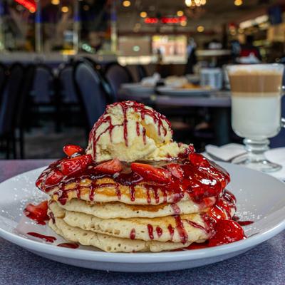 Pancakes topped with strawberries and ice cream served with Latte.