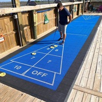 Outdoors, a person standing on a shuffleboard court.