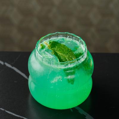 Vibrant green cocktail with mint garnish on a dark marble counter.