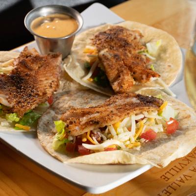 Fish tacos, served on a plate, front view.