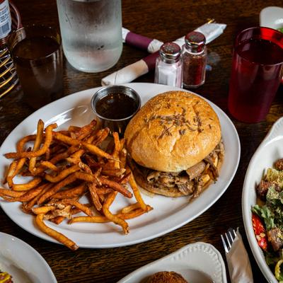 A beef on weck sandwich served with french fries and dipping sauce.