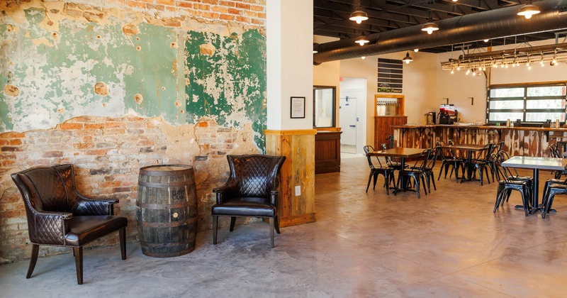 Interior with exposed brick walls, leather chairs, wooden tables, and a bar