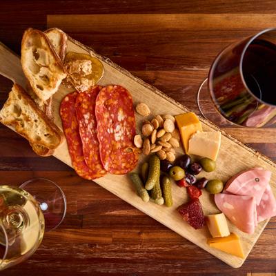 Charcuterie and cheese board served with glasses of red and white wine.