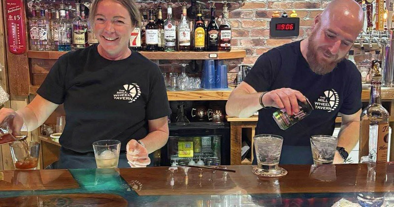Two bartenders mixing drinks behind the bar