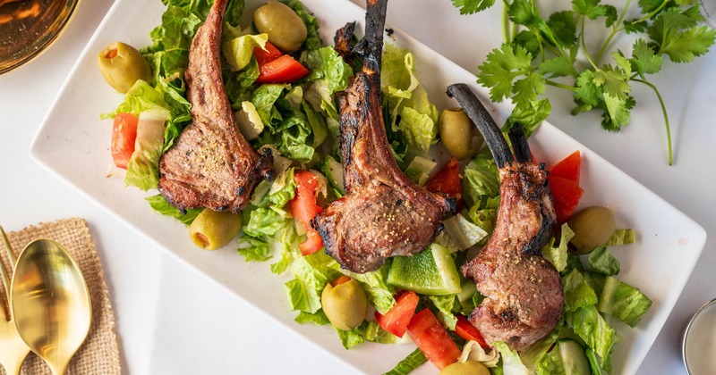 Lamb Chops, served on the bed of lettuce, vegetables, and olives