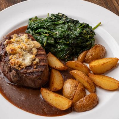 Sauce-topped filet mignon served with roasted potato wedges and spinach.