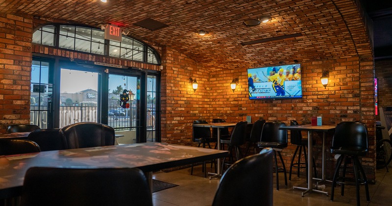 Interior, tall tables and bar chairs, TV on a brick wall