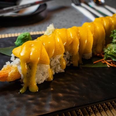 Mango Roll with shrimp tempura and mango slices drizzled with a bright yellow sauce.