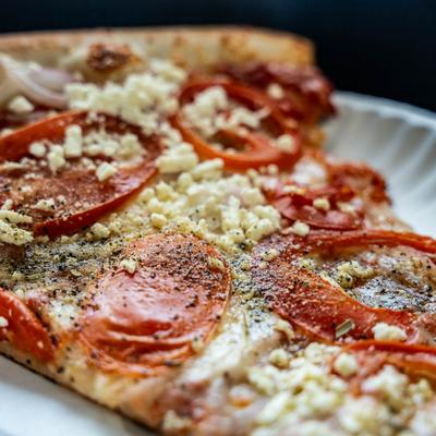 White pizza slice with tomatoes, onions, and feta cheese, close-up.