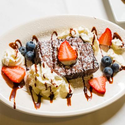 Chocolate brownie served with berries and whipped cream.