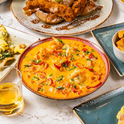 A vibrant bowl of creamy shrimp and grits dish, surrounded by assorted food plates.