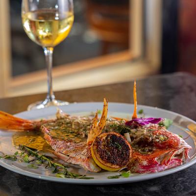 Whole red snapper dish, served with a glass of white wine