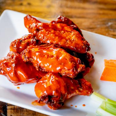 Chicken wings coated in sauce served with celery sticks.