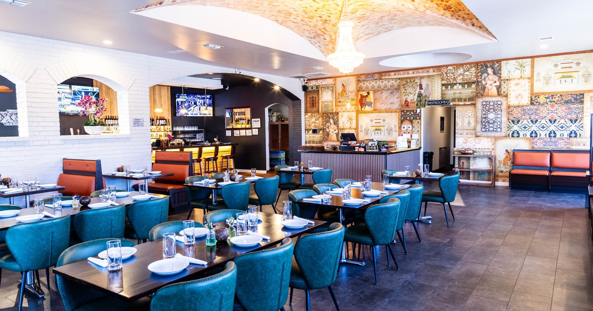 Modern interior with teal chairs, set tables, a bar and decorative wall art