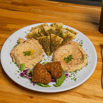 Hummus served with toasted pita triangles topped with za'atar spices and falafel.