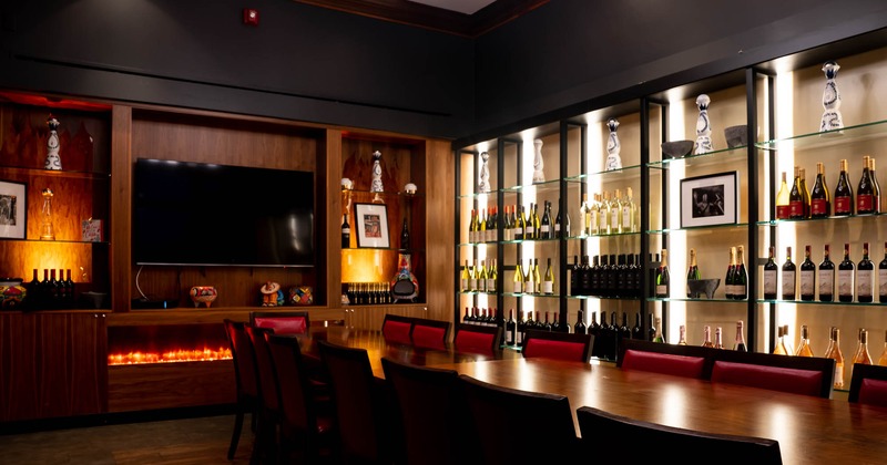 Seating area with wine bottles on glass shelves, decorations, TV and  a fireplace