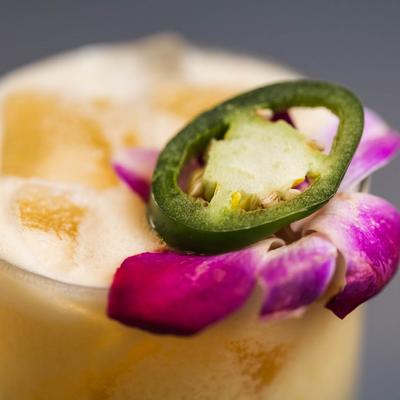 Close up of Margarita with jalapeno and flower garnish.