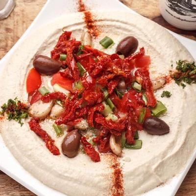 Mediterranean hummus with tomatoes, olives, roasted garlic and feta, top view