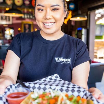 Smiling Staff woman serving basket of nachos